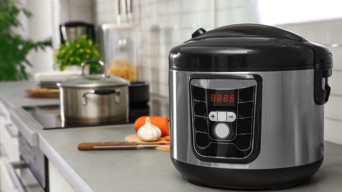 Panela de pressão elétrica moderna em bancada de cozinha com legumes ao lado — eletrodoméstico que economiza tempo e dinheiro no preparo das refeições
